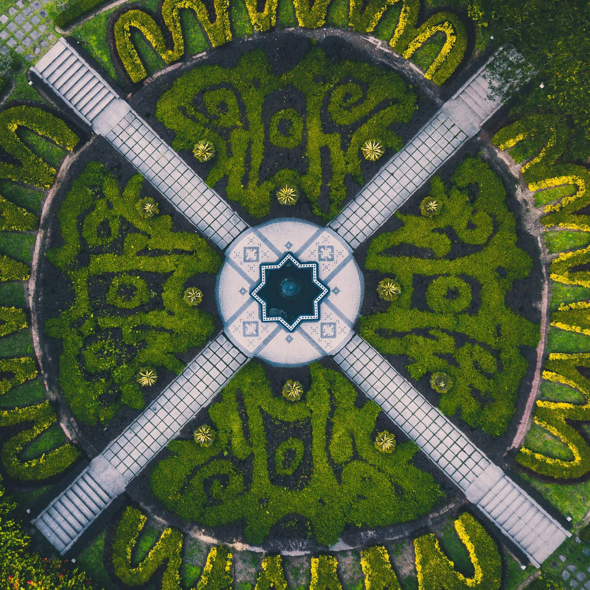 Giardino geometrico visto dall'alto con vialetti e fontana centrale